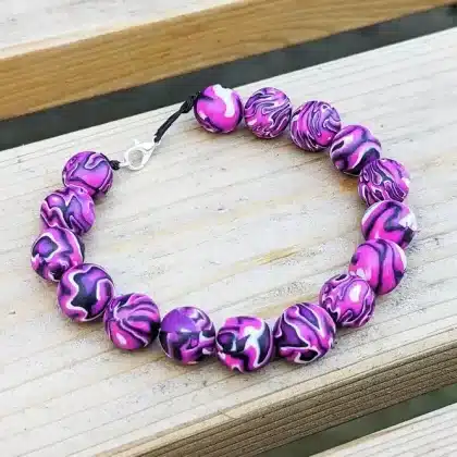 purple beaded bracelet with psychedelic pattern, shot under natural light on wooden background